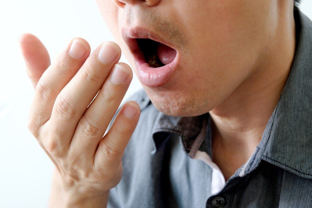 homme qui vérifie s'il a mauvaise haleine