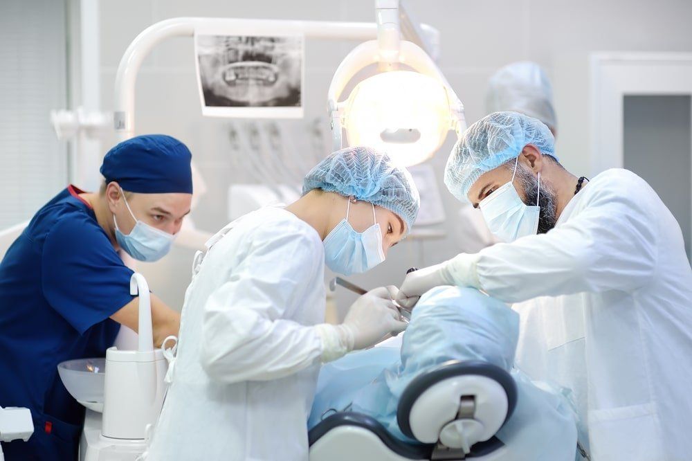 Un dentiste et ses assistantes réalisent une chirurgie dentaire