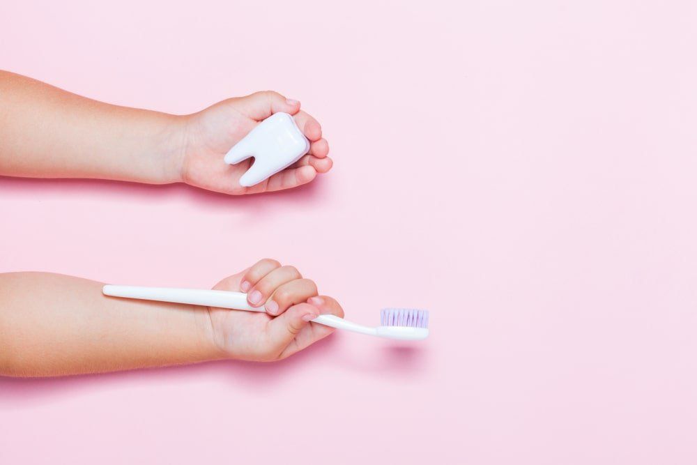 mains d'enfant avec brosse à dents