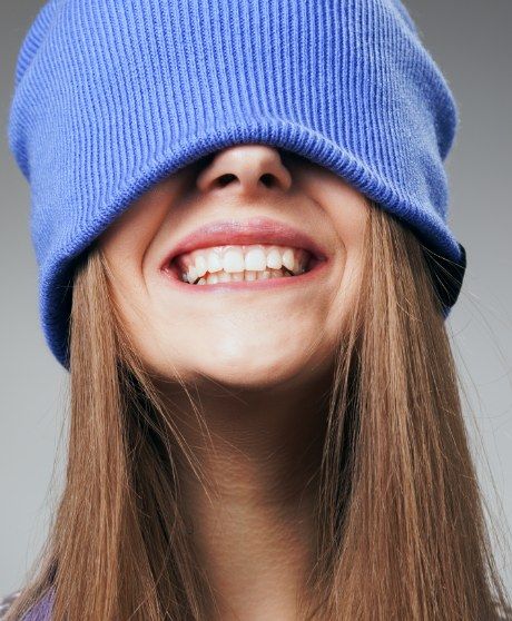 Une jeune femme sourit, sa tuque bleue rabattue sur les yeux.