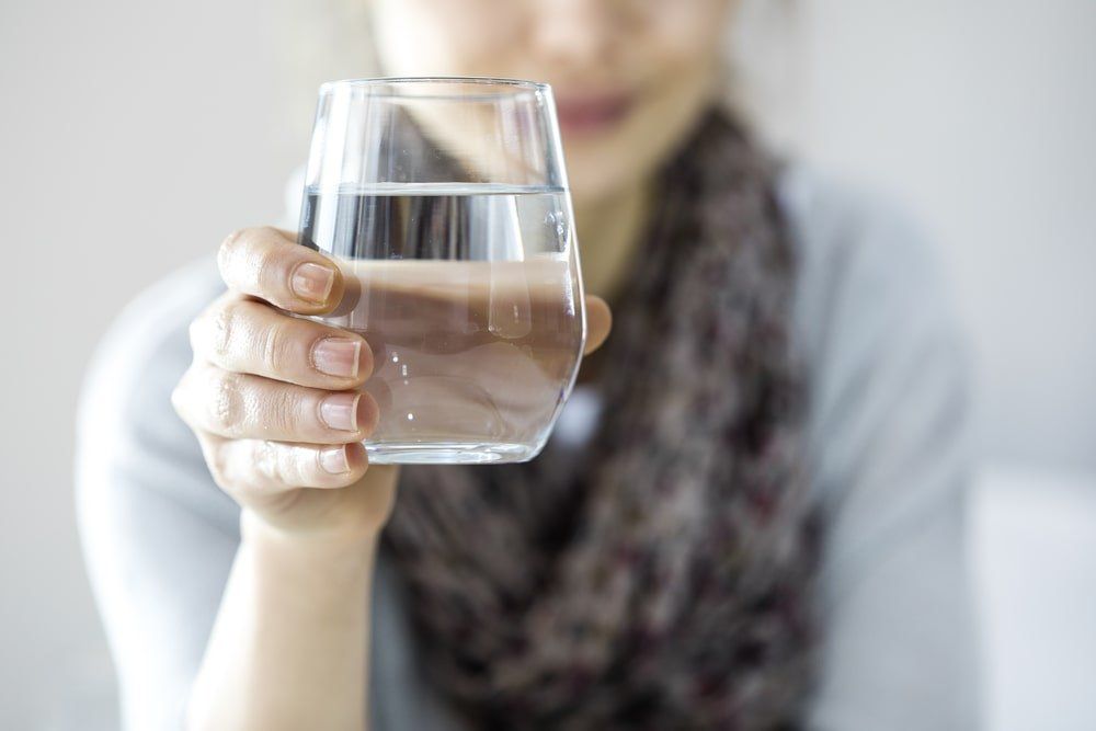 gros plan sur un verre d'eau tenu par une femme
