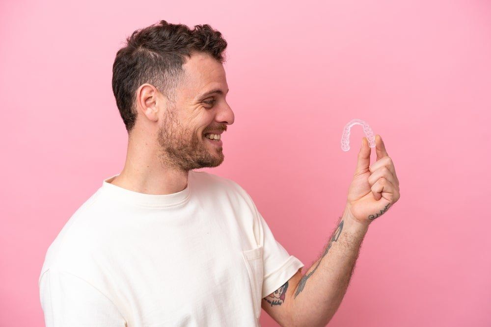 Un homme montre ses gouttières d'orthodontie invisible