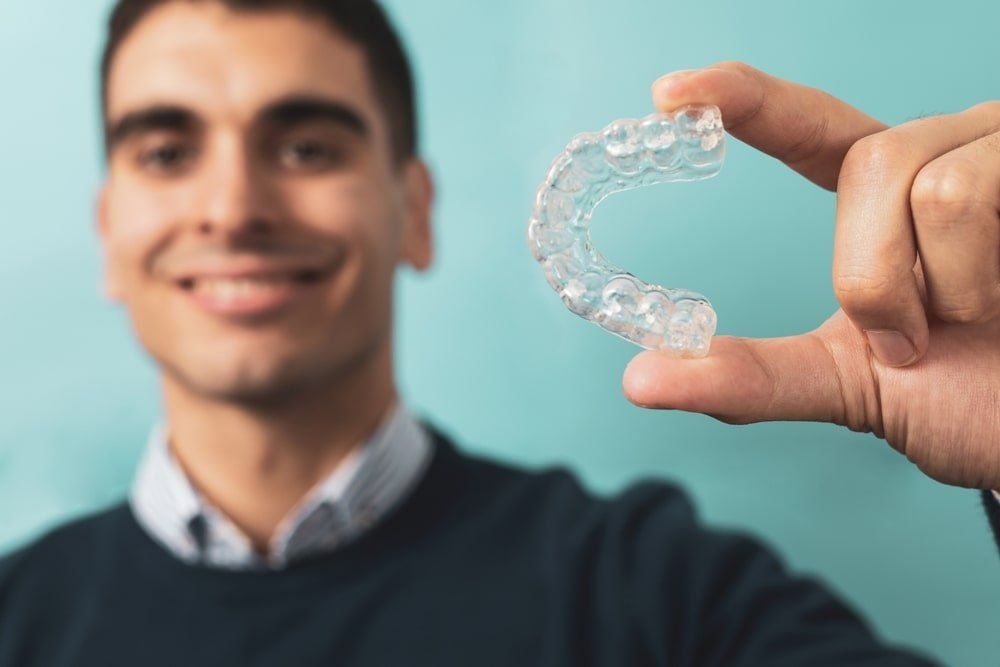 Un homme montre des gouttières utilisées pour l'orthodontie invisible