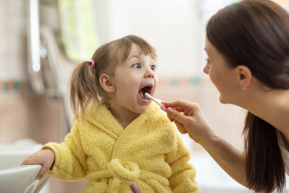 Mère brossant les dents de sa fillette