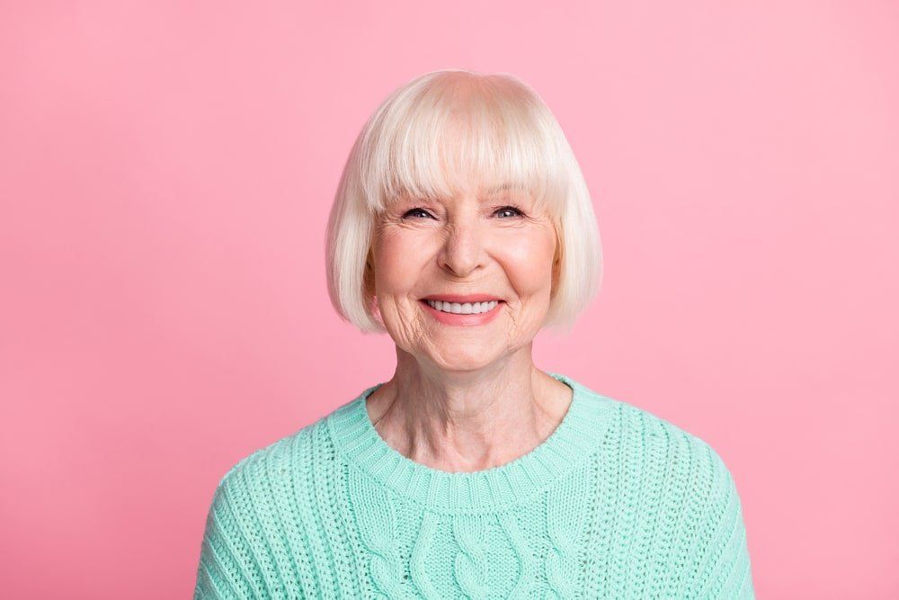 vieille dame souriante sur fond rose