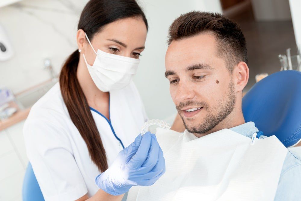 dentiste qui présente un traitement d'orthodontie à un homme adulte